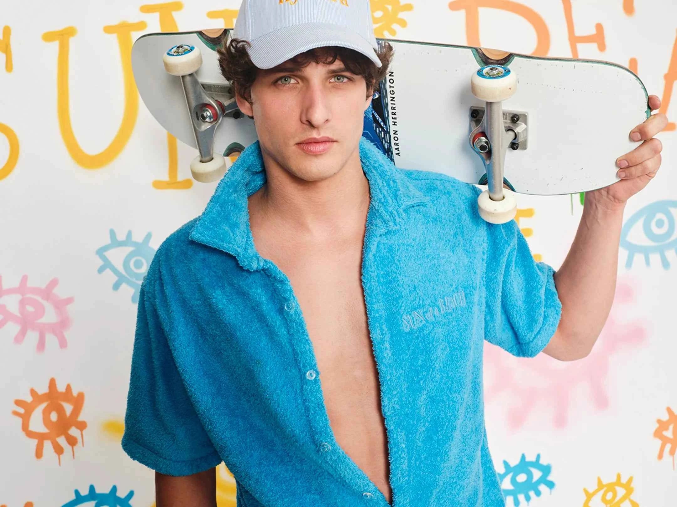 Man holding a skateboard with a colorful background