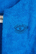 Close-up of a blue textured fabric with an embroidered eye design, featuring the brand 'Coach'.