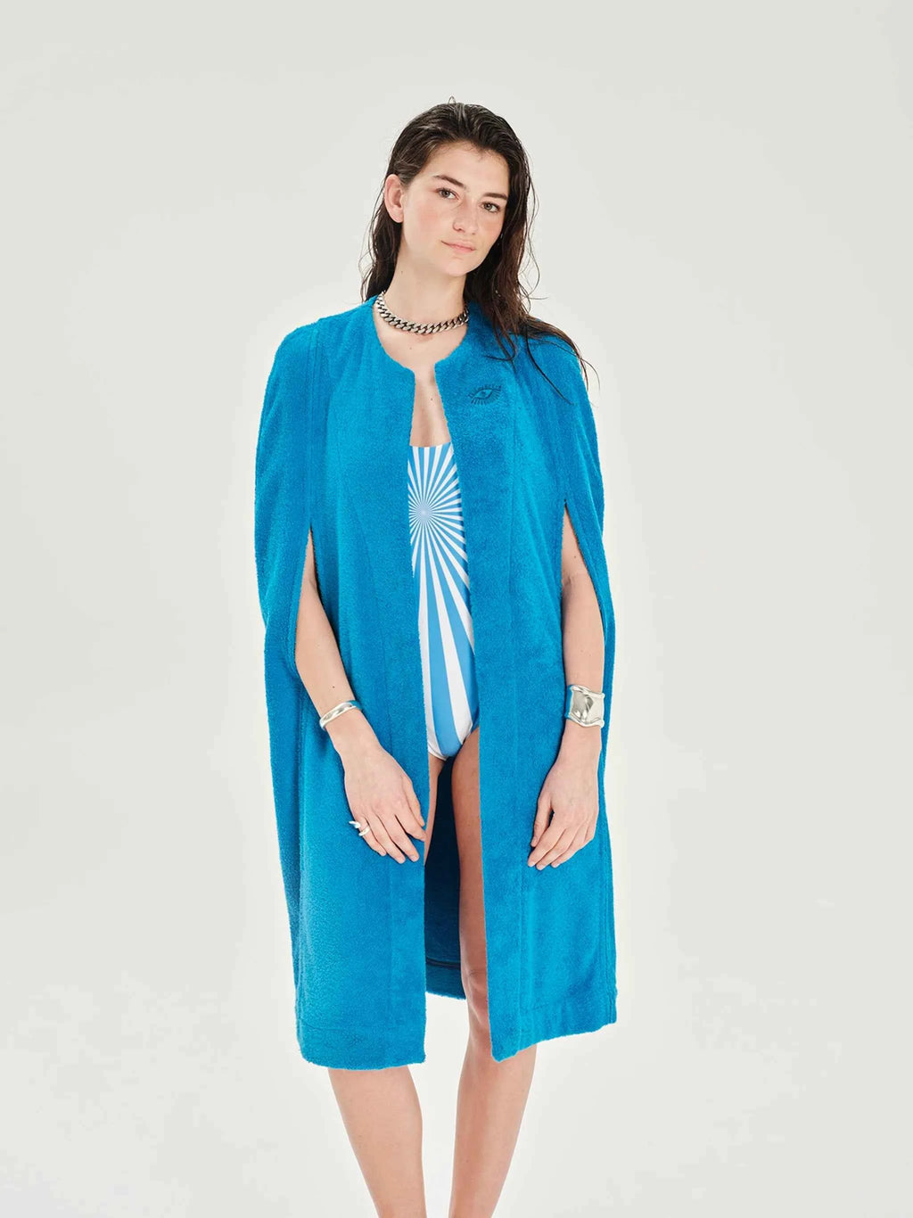 Woman wearing a blue cover-up over a swimsuit on a white background