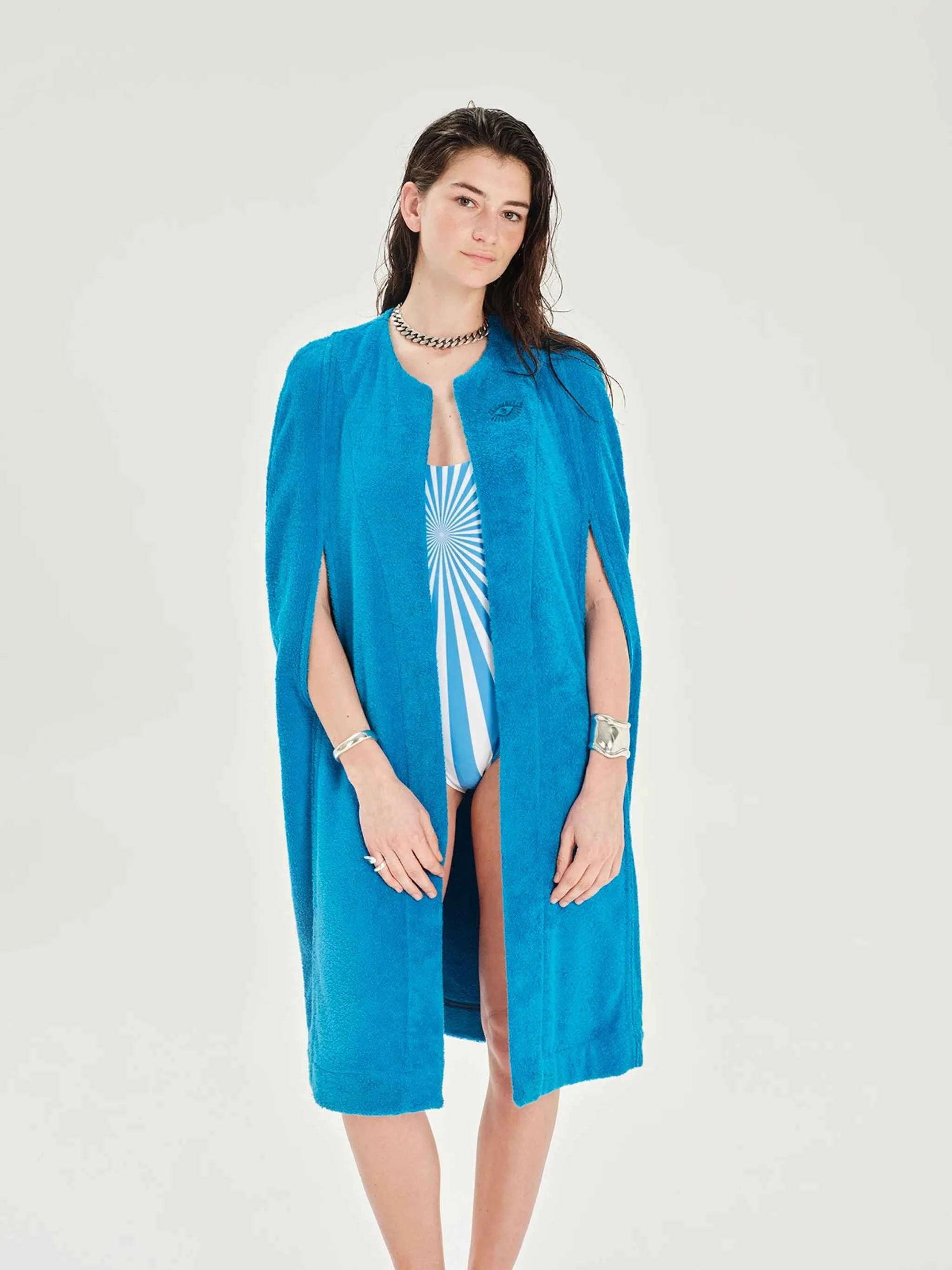 Woman wearing a blue cover-up over a swimsuit on a white background