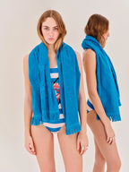 Woman wearing a blue scarf and striped swimsuit on a plain background