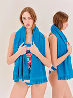 Woman holding a blue towel over her shoulder against a plain background
