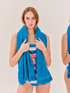 Woman wearing a blue towel over her shoulders with a plain background