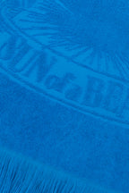 Close-up of a blue towel with branding and fringes