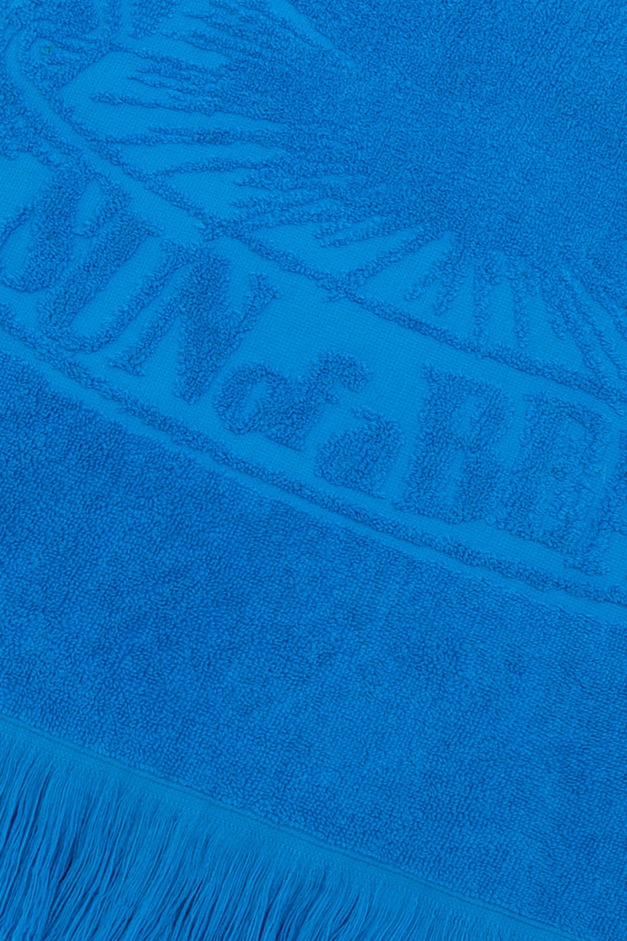 Close-up of a blue towel with branding and fringes