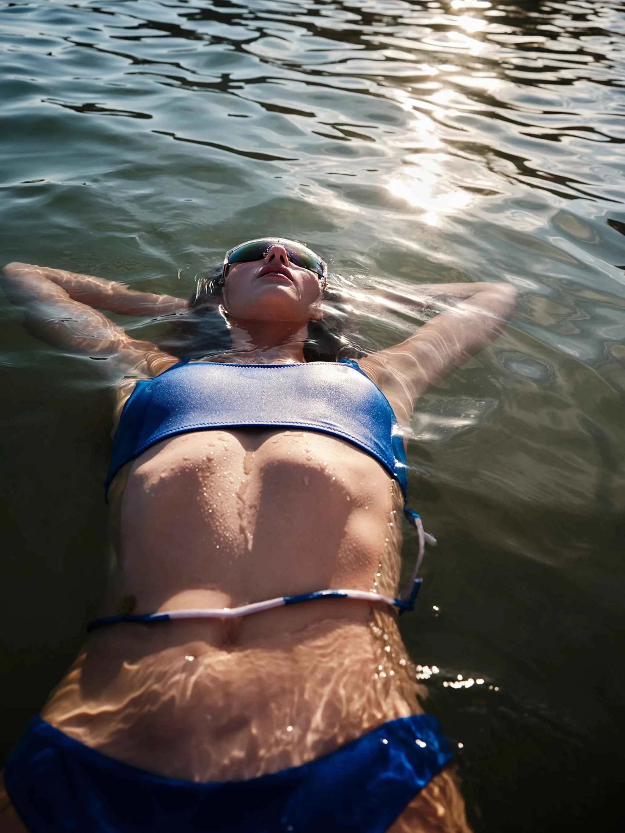 Person floating in water wearing a blue swimsuit and goggles