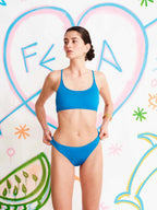 Woman wearing a blue bikini against a colorful abstract background