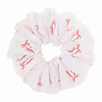 White scrunchie with red bow pattern on a white background