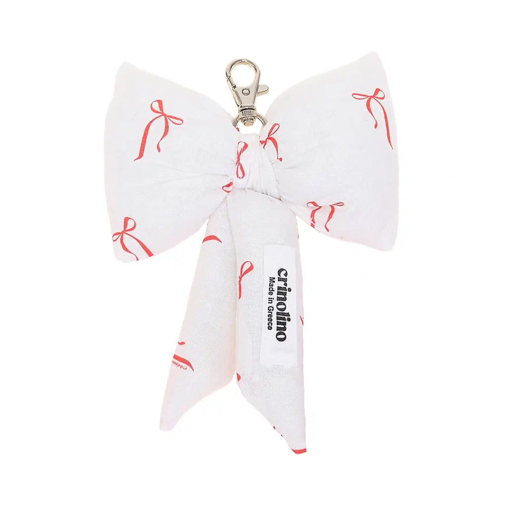 White bow-shaped keychain with red bows pattern and 'crinolino' branding on a white background