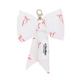 White bow-shaped keychain with red bows pattern and 'crinolino' branding on a white background