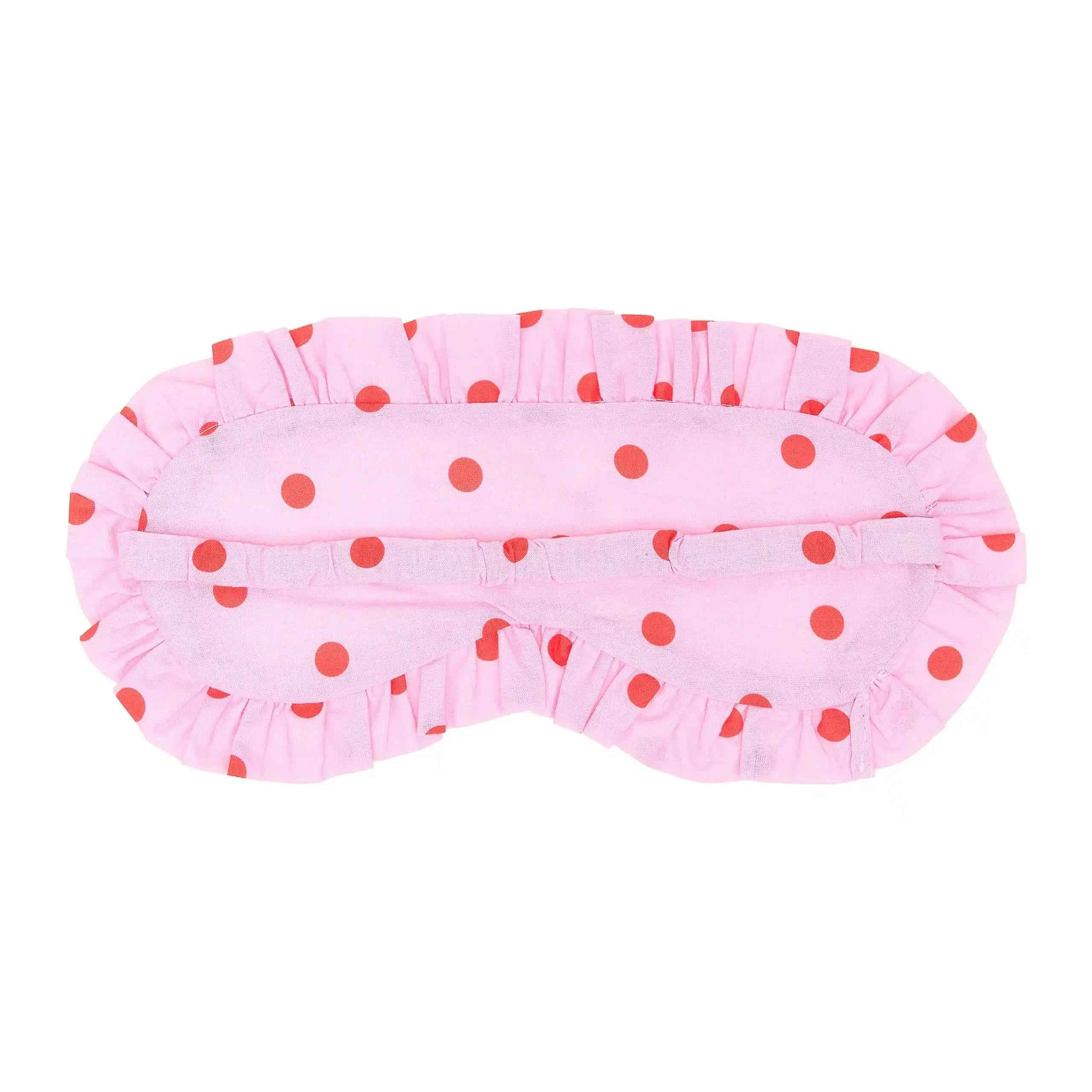 Pink sleep mask with red polka dots on a white background