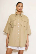 Woman wearing a beige shirt with pocket details on a white background