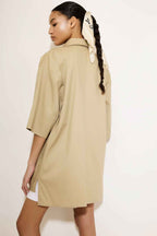 Woman wearing a beige trench coat with a plain background