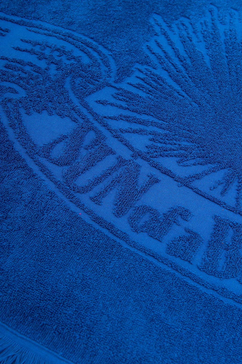 Close-up of a blue towel with branding text and logo.
