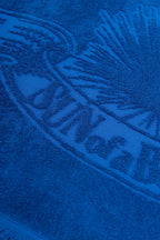 Close-up of a blue towel with branding text and logo.