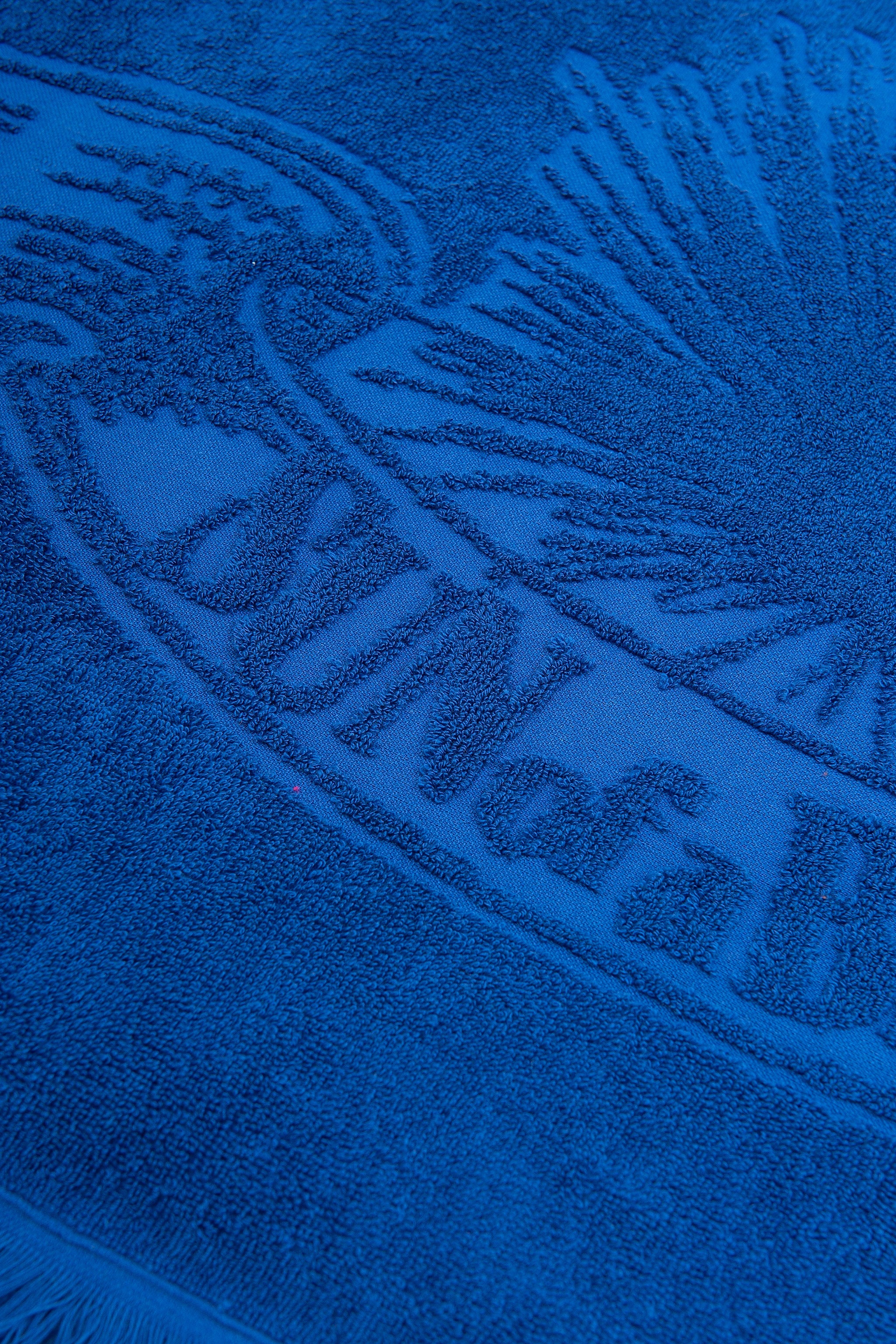 Close-up of a blue towel with branding text and logo.