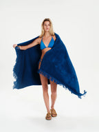 Woman wearing a blue bikini and cover-up on a white background