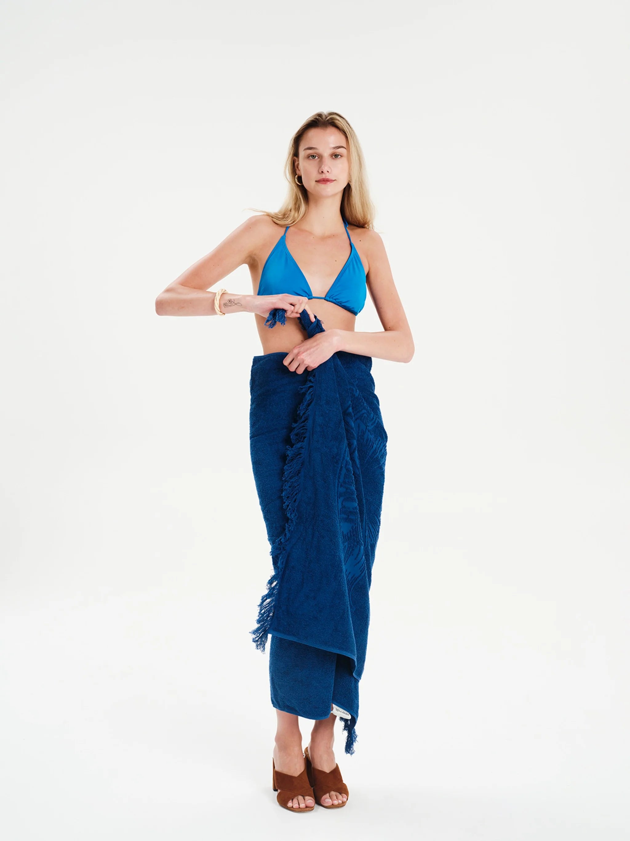 Woman wearing a blue bikini and sarong on a white background