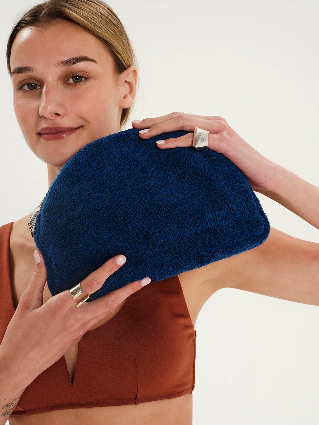 Woman holding a blue clutch against a neutral background