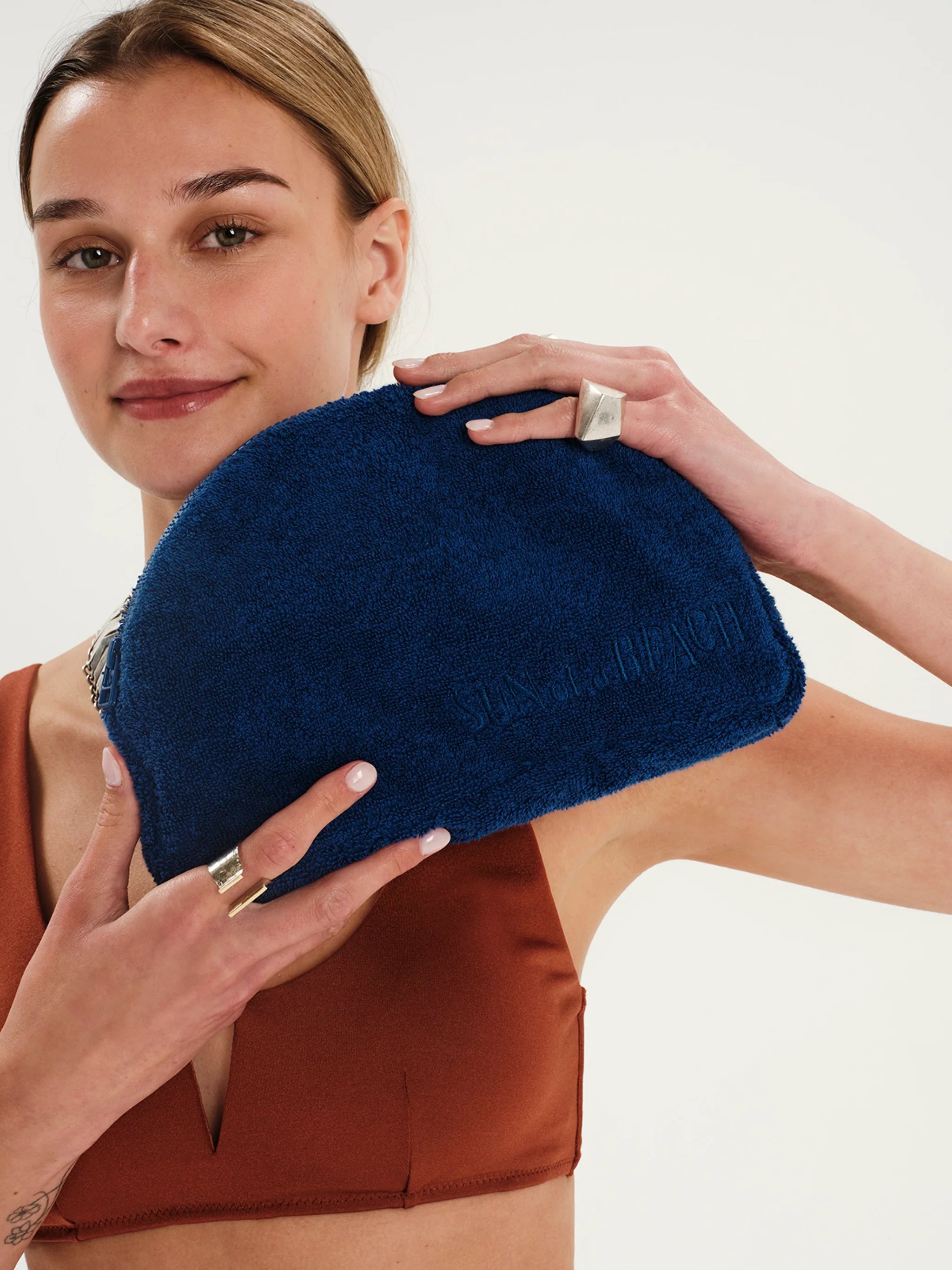 Woman holding a blue clutch against a neutral background