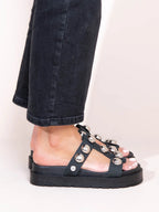 Black sandal with pearl embellishments worn with black jeans on a white background