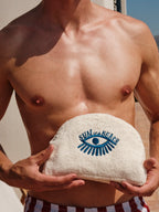 Man holding a towel with 'Sun of a Beach' logo against a neutral background