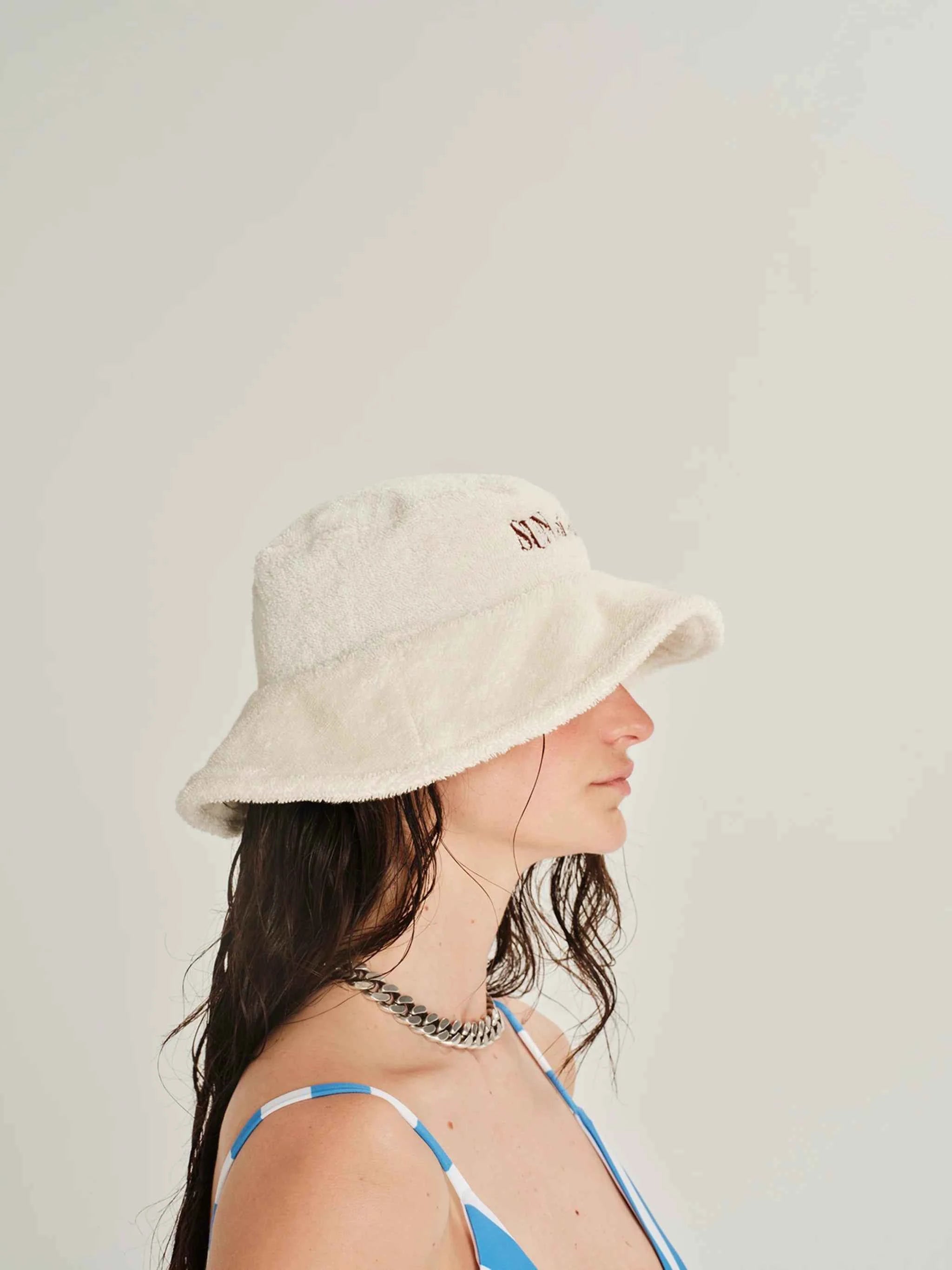 Woman wearing a beige bucket hat against a plain background