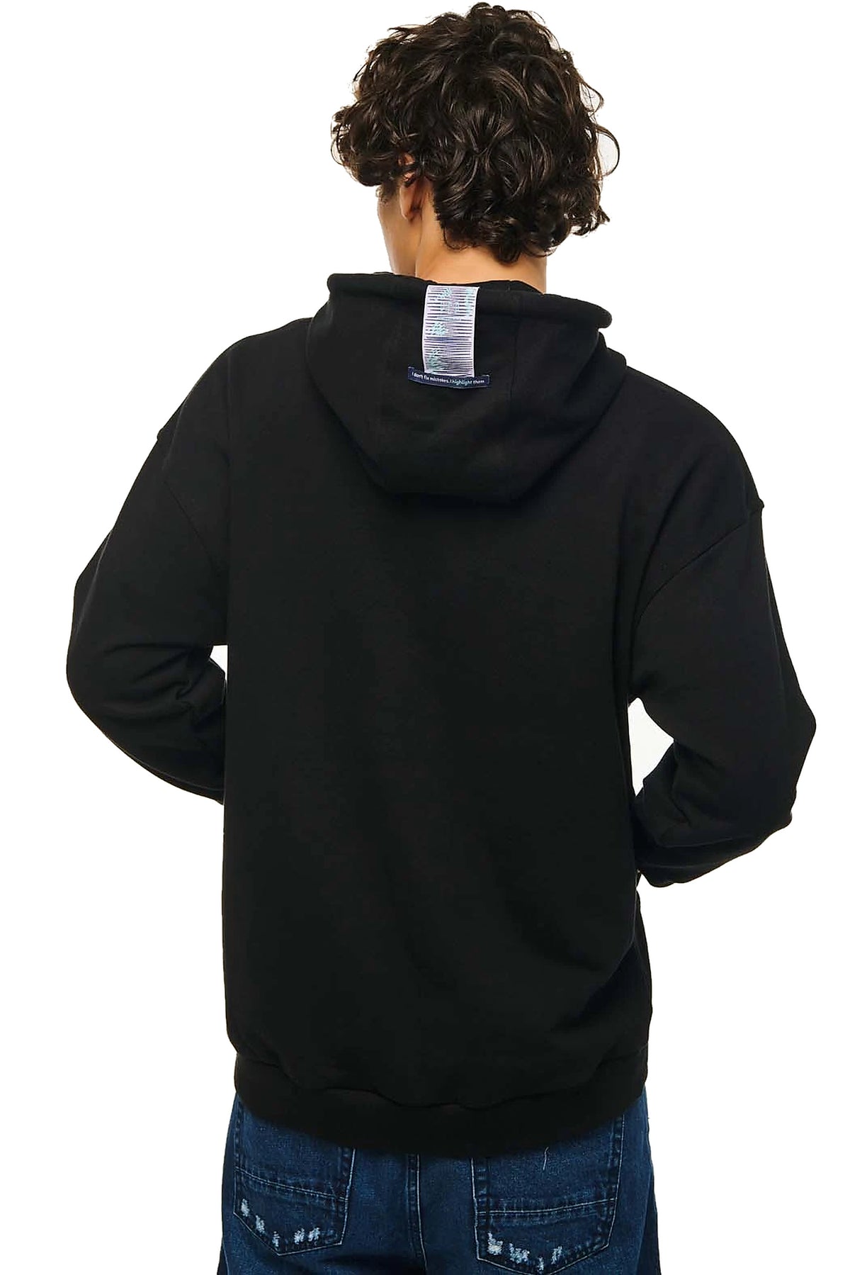 A person shown from the back wearing a black pullover hoodie and blue jeans against a plain white background.