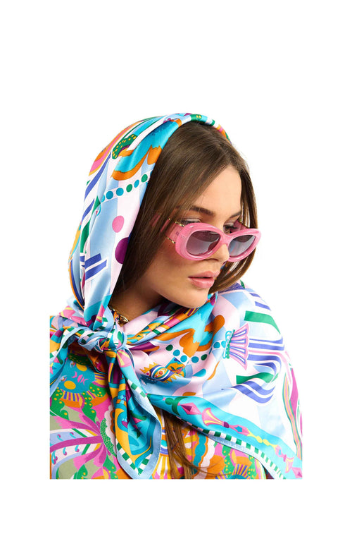 Woman wearing a colorful patterned scarf and sunglasses on a white background