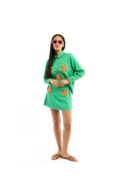 Woman wearing a green outfit with orange accents on a white background