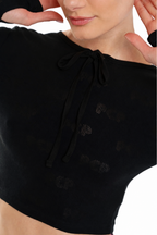 Close-up of a model wearing a black knit crop top with a tie-neck detail and subtle tonal dotted pattern.