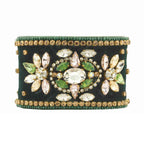 Decorative bracelet with green and gold stones on a white background
