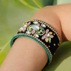 Decorative bracelet with gemstones on a wrist against a natural background