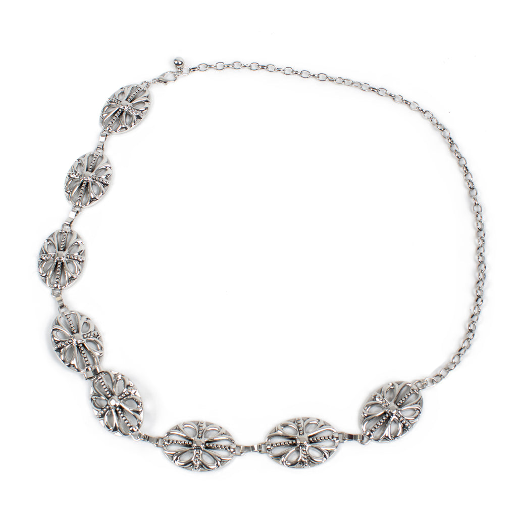 A silver-toned chain necklace featuring five ornate, textured oval links with intricate floral and scrollwork details, displayed on a clean white background.