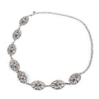 A silver-toned chain necklace featuring five ornate, textured oval links with intricate floral and scrollwork details, displayed on a clean white background.