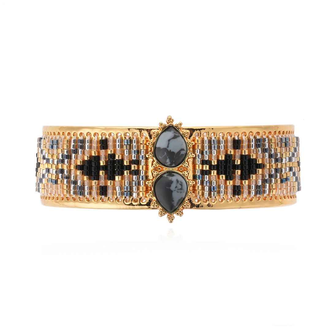 Gold and black beaded bracelet with two central stones on a white background