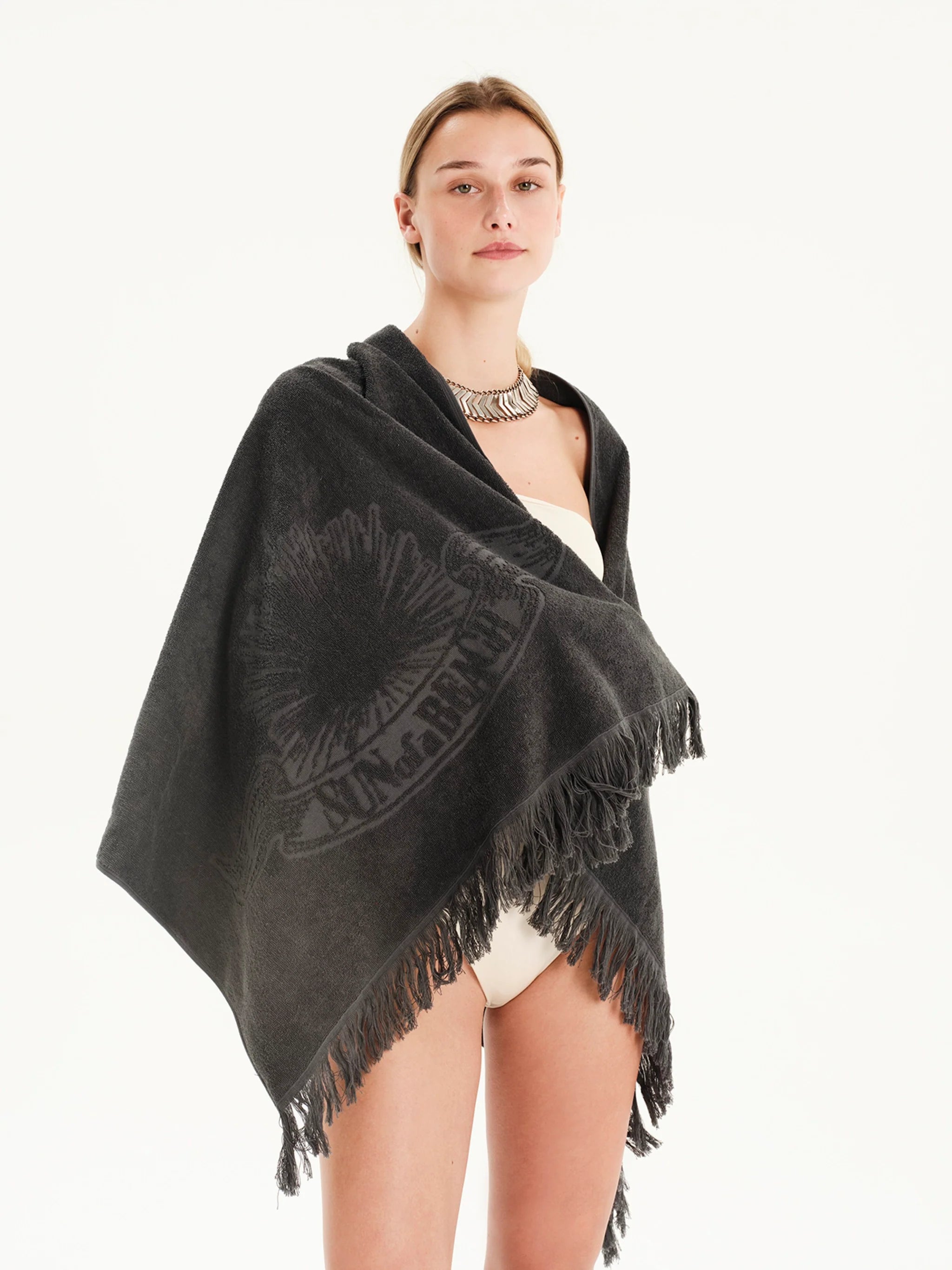Woman wearing a black poncho with fringe on a white background