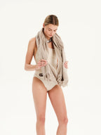 Woman wearing a beige scarf and tank top on a white background