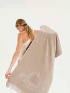 Woman holding a beige towel with a brand logo on a white background