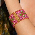 Decorative bracelet with pink and green floral patterns on a wrist.