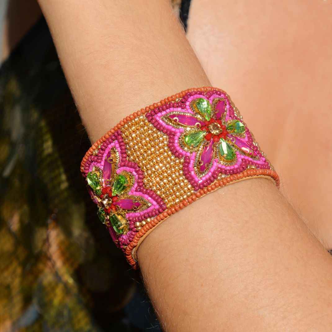 Decorative bracelet with pink and green floral patterns on a wrist.