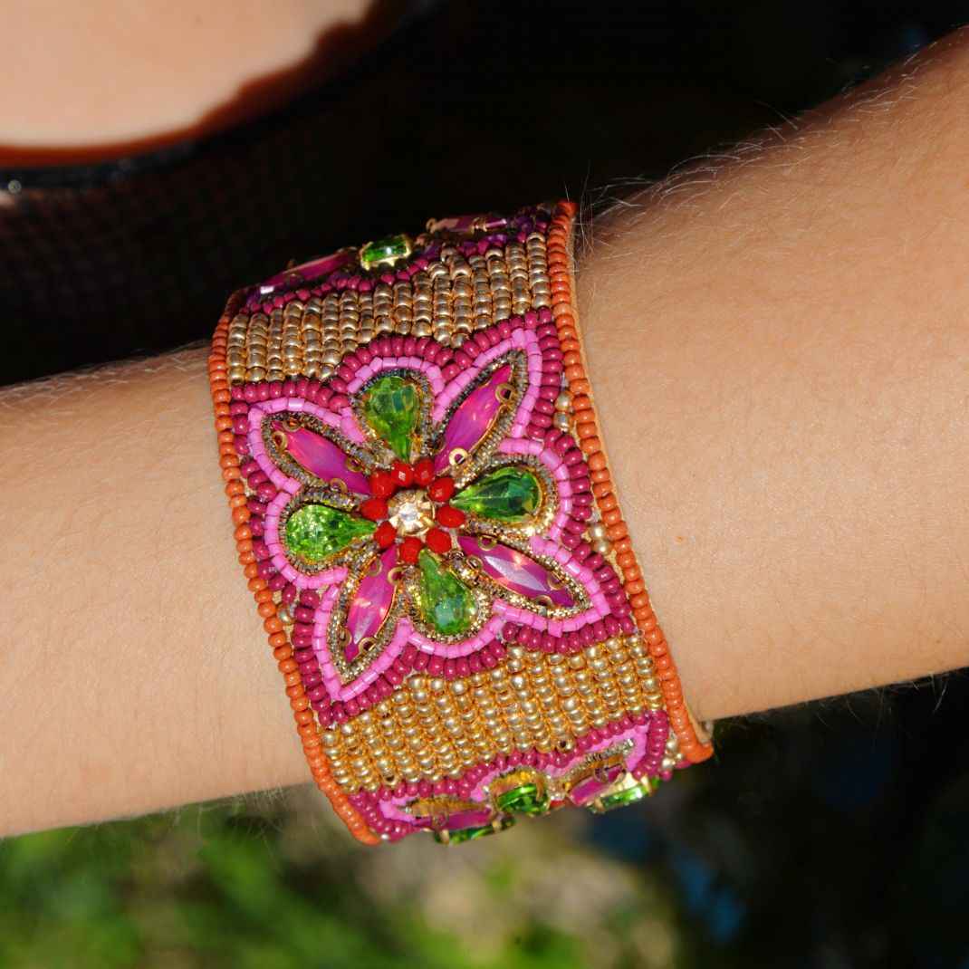 Decorative bracelet with floral design on a wrist against a blurred background