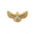 Gold emblem with wings and a turquoise stone on a white background