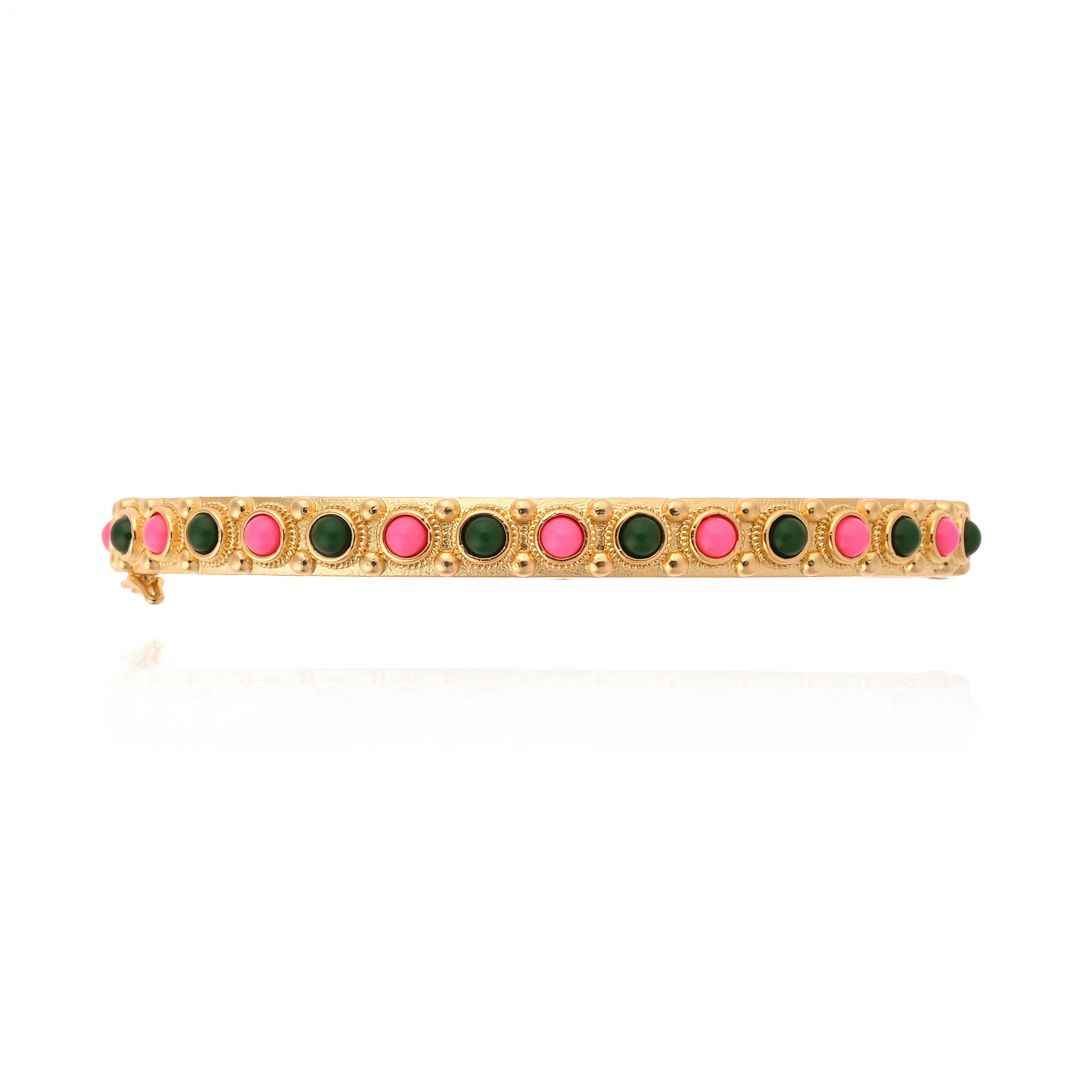 Bracelet with green and pink stones on a gold band against a white background