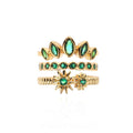 Set of gold rings with green gemstones on a white background