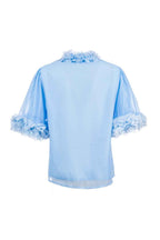 Light blue blouse with ruffled details on a white background