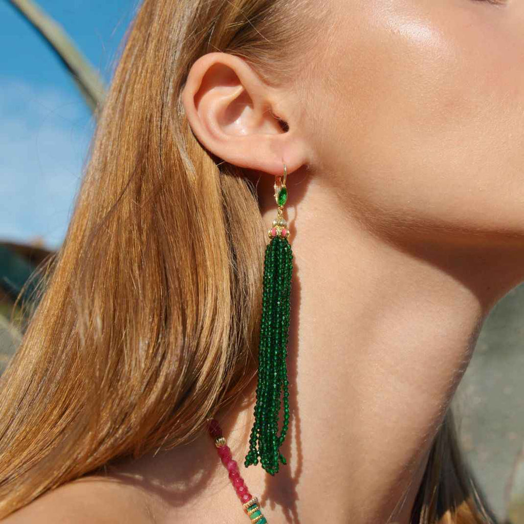 Close-up of a person wearing green beaded earrings with a blurred background
