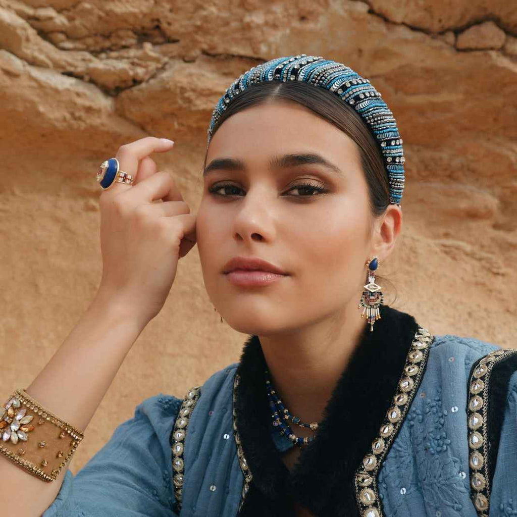 Woman wearing traditional jewelry against a desert backdrop