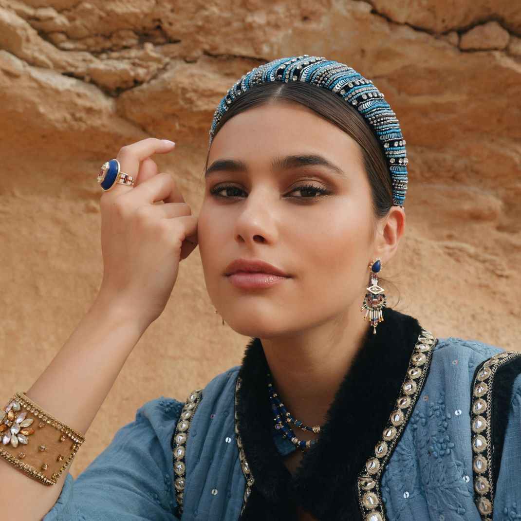 Woman wearing traditional jewelry against a desert backdrop