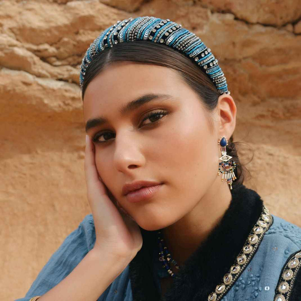 Woman wearing a decorative headband and earrings against a desert background